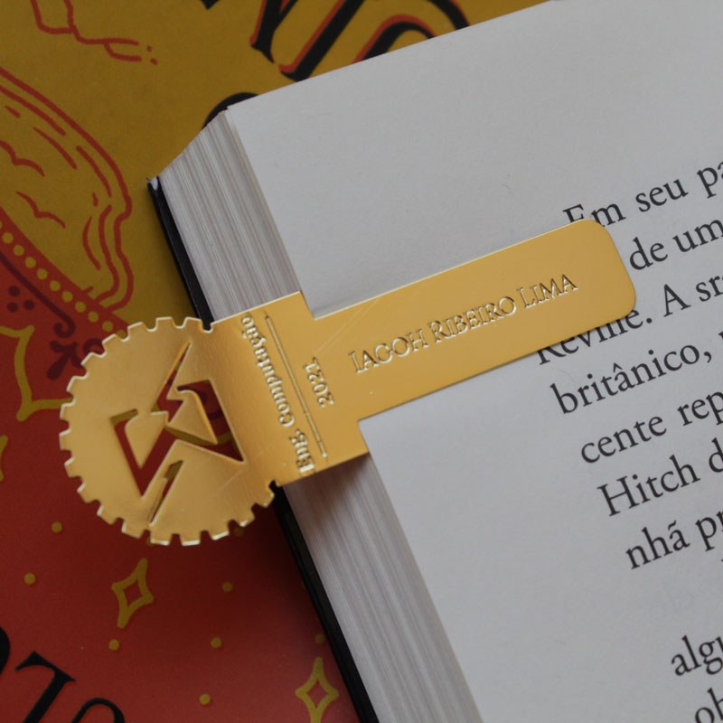 Marcador de página dourado de Engenharia da Computação encaixado em um livro
